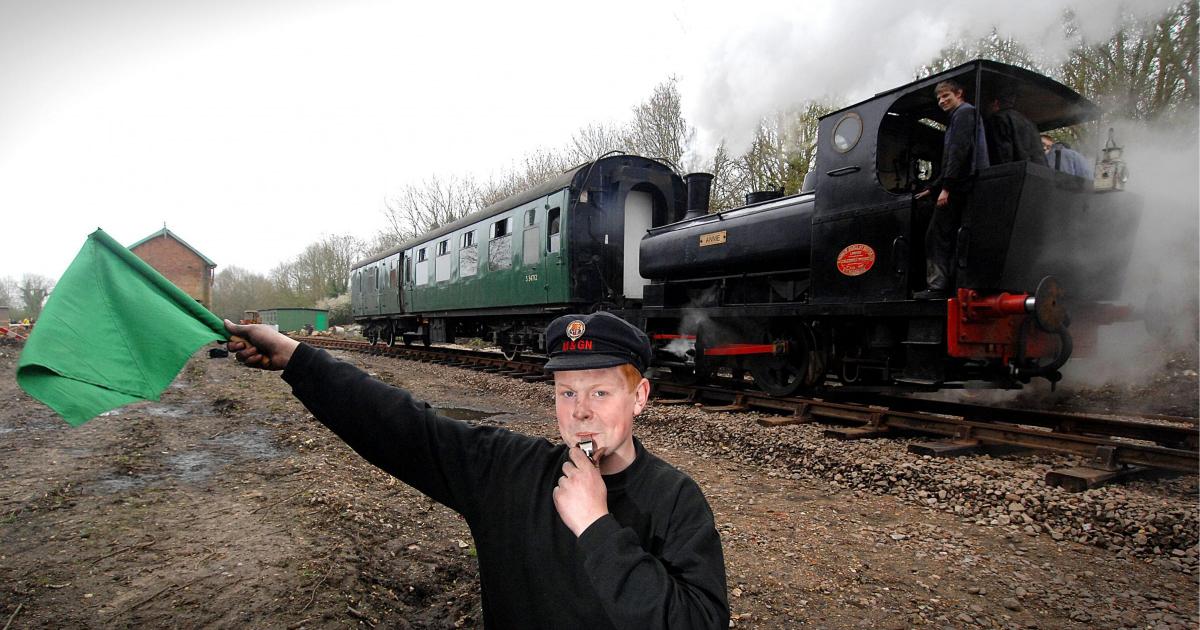 A vintage enthusiast signalling the start of a steam train journey.